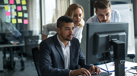 Three business professionals working at a computer