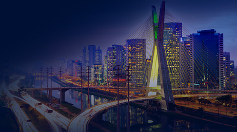 A composite image of a freeway system with several suspended bridges around a brightly lit city with a deep indigo background