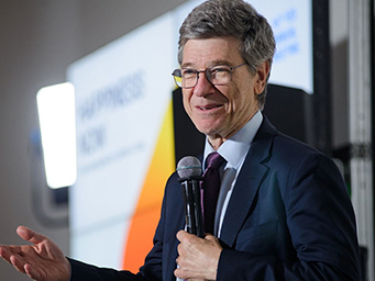  Economist Jeffrey Sachs smiling while presenting with a mic in hand