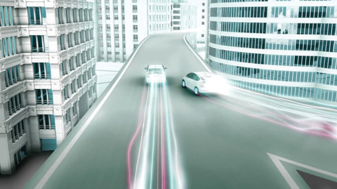View down street of two Prius' with light trails following their driving path.